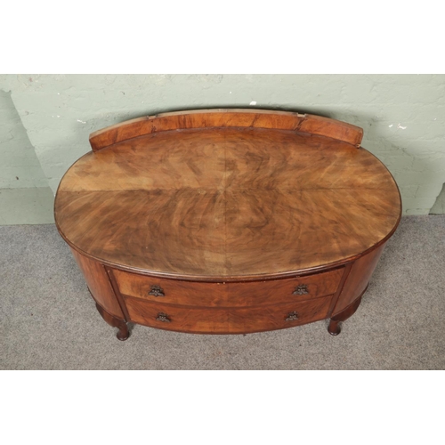 473 - A walnut veneer oval shaped dressing table with quarter veneer top and two drawers