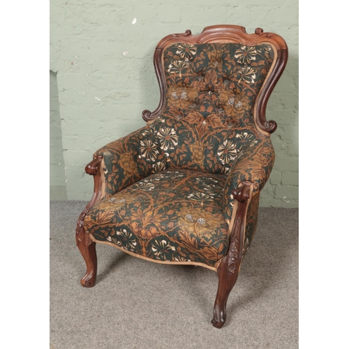 486 - A Victorian walnut scrolling carved button back armchair with William Morris Honeysuckle upholstery