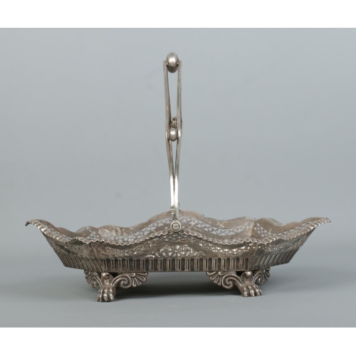 120 - An Edwardian silver basket with swing handle, pierced decoration and raised on four paw feet. 628g.