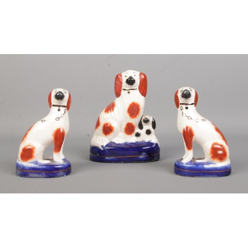 13 - A pair of 19th century Staffordshire dogs along with another example with puppy. Height 15cm.