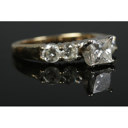 141 - A 14ct yellow gold diamond ring. Set with a central square cut diamond flanked either side by two br... 