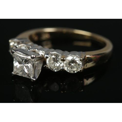 141 - A 14ct yellow gold diamond ring. Set with a central square cut diamond flanked either side by two br... 