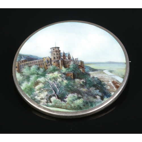 146 - A continental silver and enamel brooch decorated with a landscape scene and castle. Stamped 800 to b... 