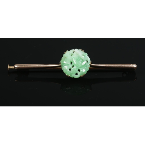 185 - A 9ct gold carved jadeite bar brooch. Maker's mark HGB. Length 6cm.