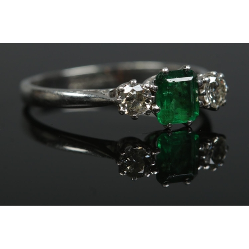 197 - An Art Deco 18ct gold and platinum emerald and diamond three stone ring. Size O. 2.46g.