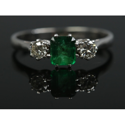 197 - An Art Deco 18ct gold and platinum emerald and diamond three stone ring. Size O. 2.46g.