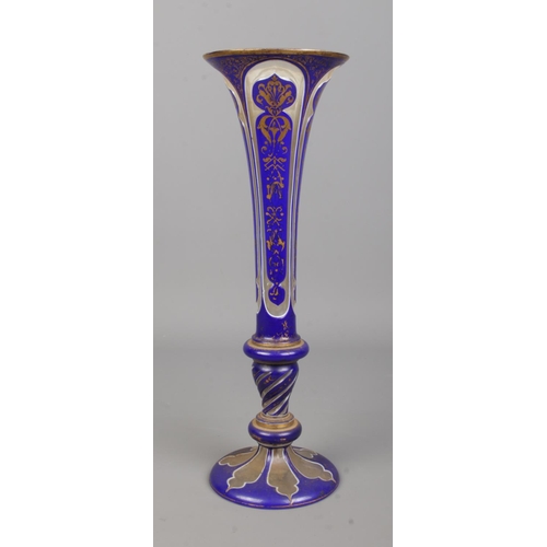 4 - A Bohemian overlay glass trumpet vase decorated in cobalt blue and gilt. Height 33.5cm.