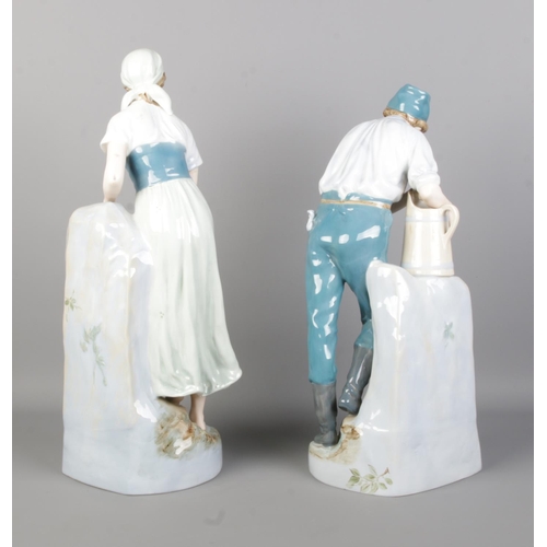 45 - A pair of Royal Dux figures modelled as male and female collecting water. Height 48cm.