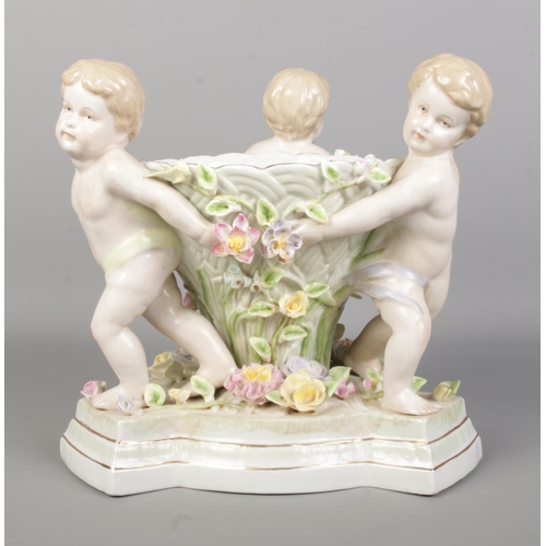 49 - A continental porcelain centrepiece formed as three cherubs holding a bowl. Height 24.5cm.