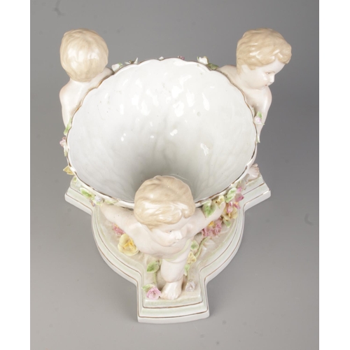 49 - A continental porcelain centrepiece formed as three cherubs holding a bowl. Height 24.5cm.