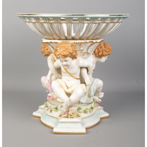 52 - A large Meissen style centre piece. With Cherub supports and pierced bowl. Height 29cm.