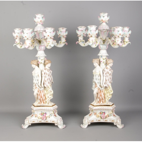 53 - A pair of Meissen style porcelain figural candelabra. Both having three maidens and applied floral d... 