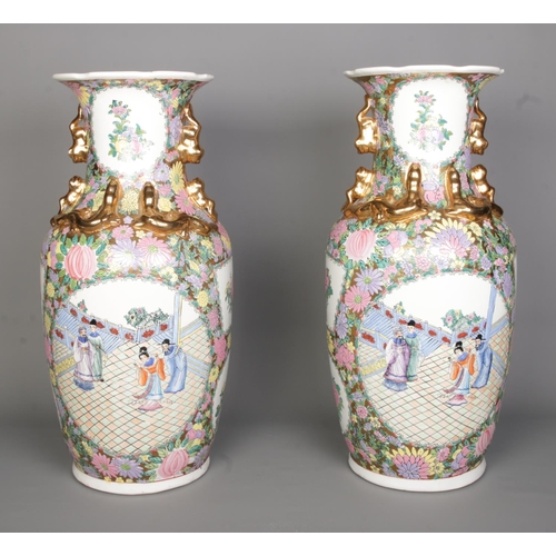 55 - A large pair of Chinese Canton famille rose vases. With panels depicting figures and floral borders.... 