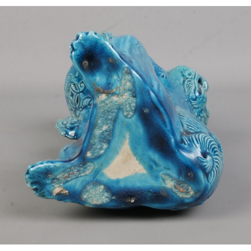 64 - A Japanese turquoise glaze lion dog in seated position holding a ball in its front paws. Height 25cm... 