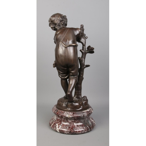 71 - After Auguste Moreau, a bronze sculpture of a boy next to a tree, raised on marble base. Signed to b... 