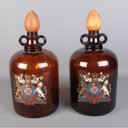 510 - A pair of amber glass demi-johns with turned wooden stoppers, each bearing heraldic coat of arms tra... 