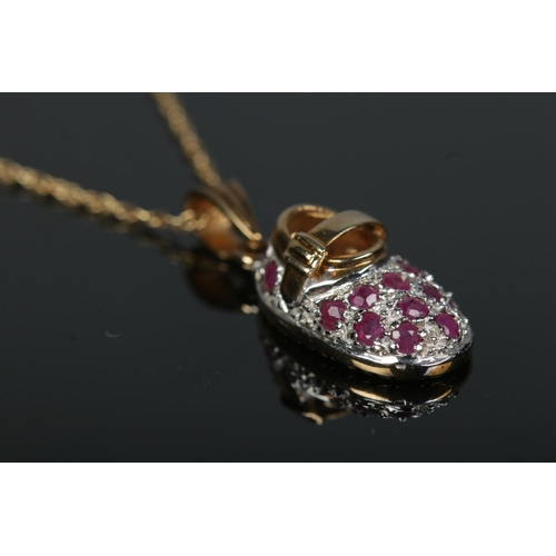 596 - A 9ct gold ruby set shoe pendant on chain.

2.95g