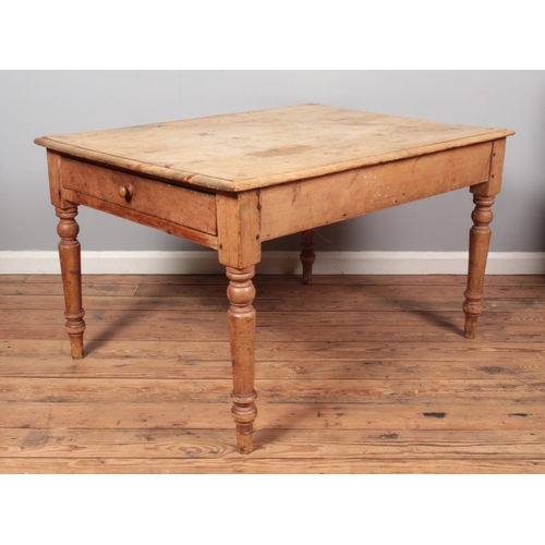 677 - A rustic rectangular pine farmhouse table, with lower drawer to one side, raised on turned supports.... 