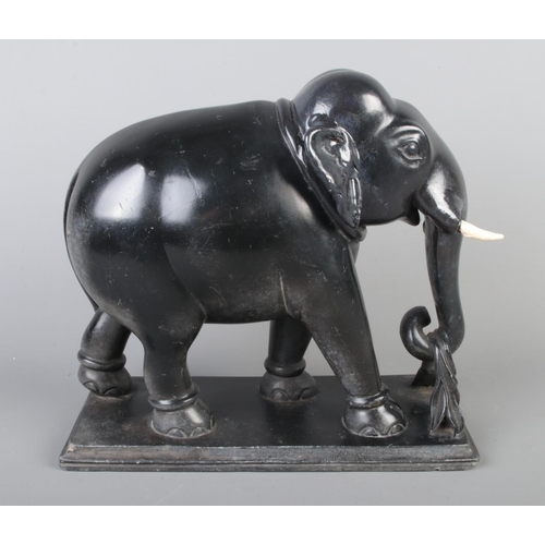 16 - A marble elephant, holding a branch, raised on stepped plinth. 25cm high.