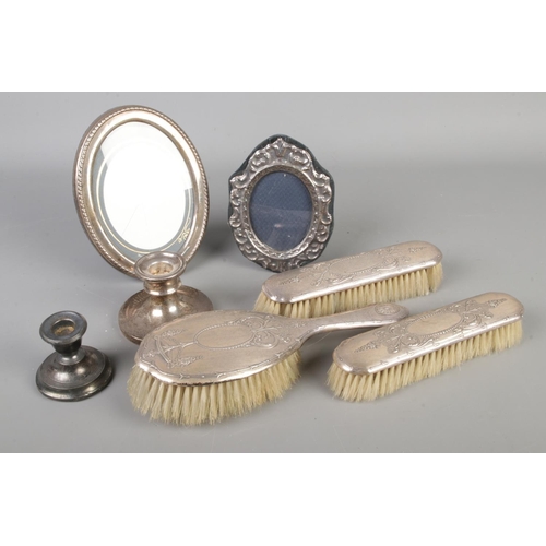 605 - A collection of silver and silver mounted items, to include candlesticks, picture frames and three p... 