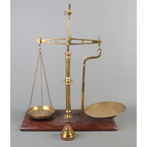 87 - A set of brass balance scales on mahogany base. With weights, some stamped for WH West, Norwich.