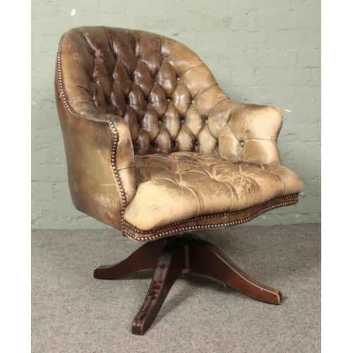 643 - A leather deep buttoned swivel arm chair.