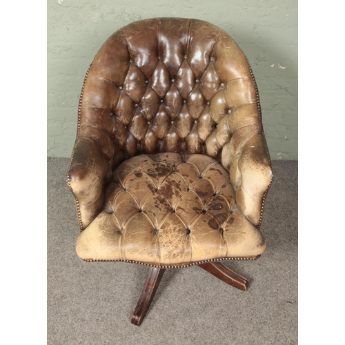 643 - A leather deep buttoned swivel arm chair.