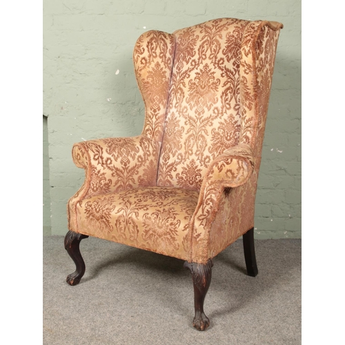 644 - A Victorian wing back arm chair raised on mahogany ball and claw supports.