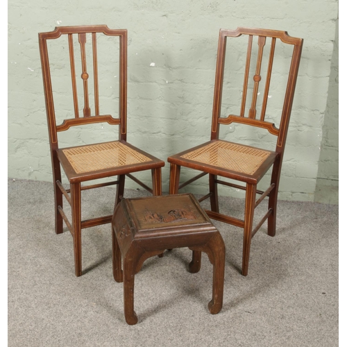 660 - A pair of Edwardian inlaid mahogany bergere seat chairs, along with a carved hardwood stool/small ta... 