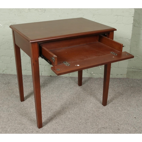 662 - A side table raised on square cut legs. Having drawer with drop down front.