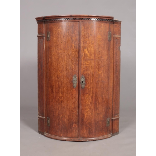 451 - A Georgian oak bow front corner cupboard. Height 99cm.