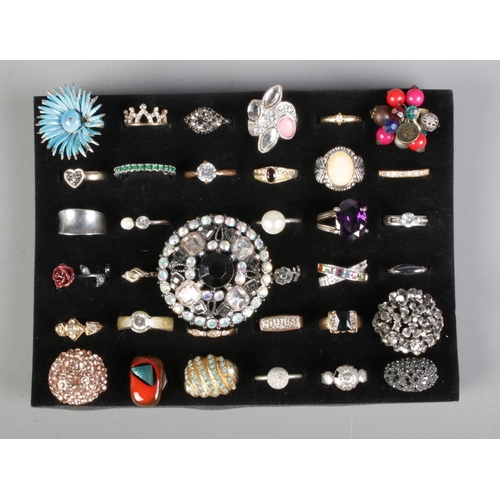 107 - A tray of 36 costume jewellery dress rings to include eternity, rose and solitaire examples.