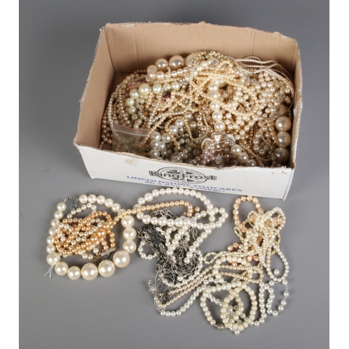 121 - A box of assorted simulated pearls to include bother necklace and bracelet examples.