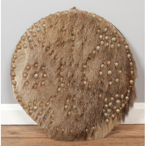 257 - A leather backed ornamental round shield with studded and deer hide covering. Diameter: 51cm.