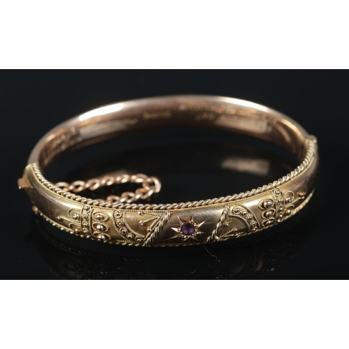 An Edwardian 9ct Gold bangle, assayed for Chester, 1902. Set with single amethyst and wirework decoration, with later inscription to the inside of the band. Total weight: 14.32g