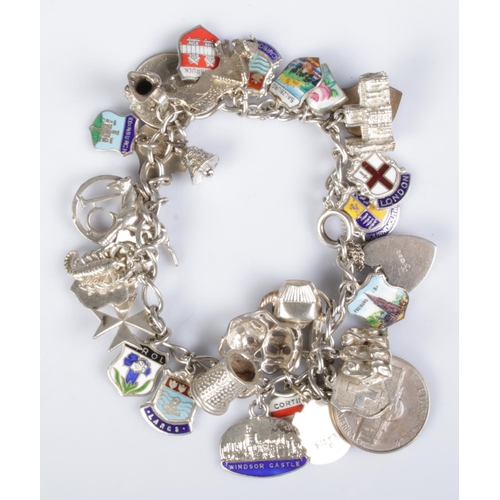 394 - A silver and white metal charm bracelet containing a large quantity of charms, including US dime, he... 