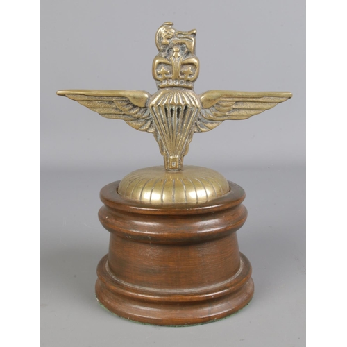 417 - A brass parachute regiment badge, formed as a car mascot, mounted on turned wooden plinth. 20cm tall... 