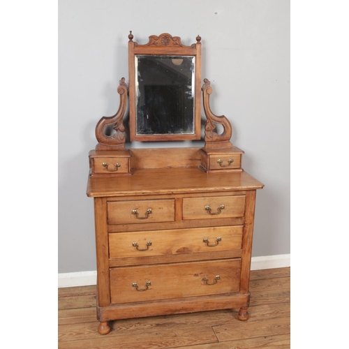 445 - A stained pine chest of drawers with swan neck handles and mirror with carved supports and drawers t... 