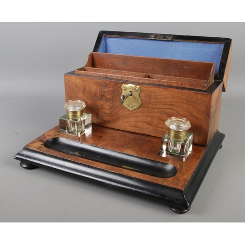 11 - An early 20th century walnut and ebonised desk tidy with ink well and brass plaque to centre, includ... 