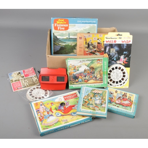 121 - A box of vintage puzzles and a 3D View Master with reels. Includes Victory, Sooty and Enid Blyton pu... 