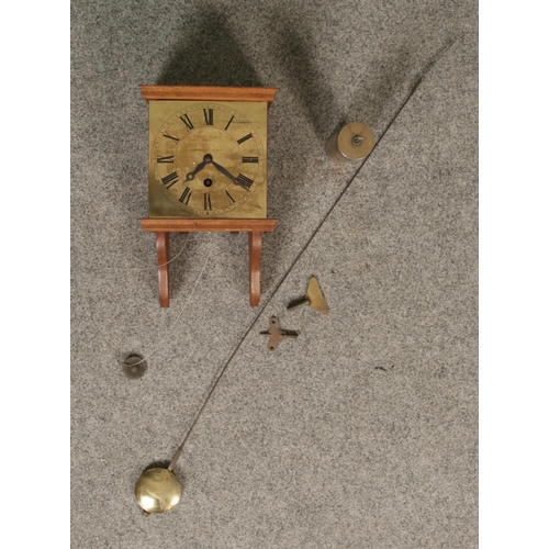 179 - An early 20th century wall clock with wooden body and brass face with roman numeral markers.