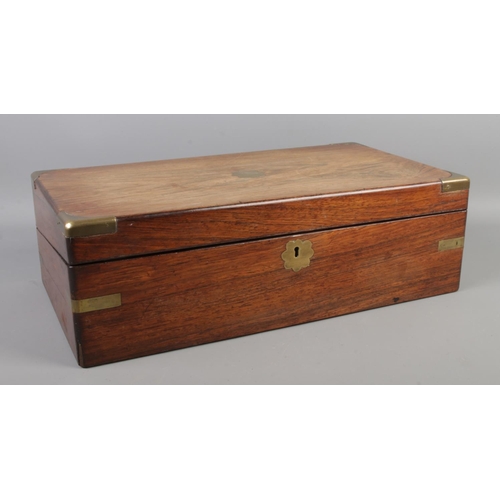 264 - A mahogany writing box with brass mounts, escutcheon and central floral plaque. The hinged top revea... 