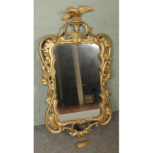 318 - A large gilt framed wall mirror mounted with outstretched eagle. Approx. dimensions 60cm x 115cm.