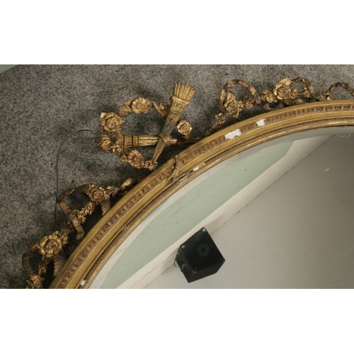 325 - A large gilt framed oval mirror decorated with crossed torches and ribbon swag detail. Approx. dimen... 