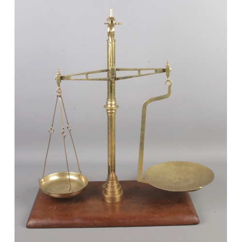 70 - A set of brass balance scales with graduating weights. Raised on wooden base.