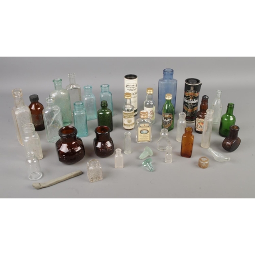 76 - A collection of assorted vintage empty glass bottles and miniature liquors.