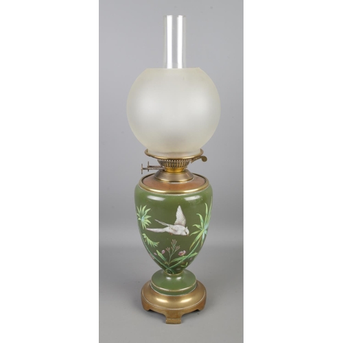 82 - A Victorian Duplex brass and ceramic oil lamp featuring painted bird amongst bamboo and frosted shad... 