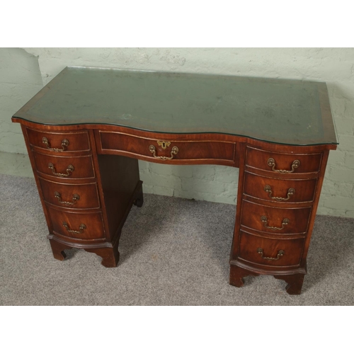 418 - A Georgian style mahogany serpentine desk with leather inset top.