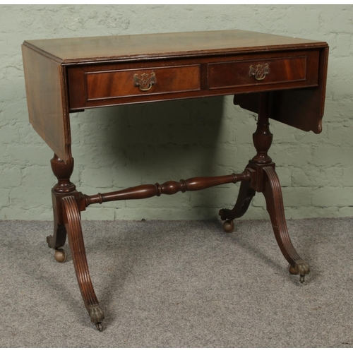 442 - A walnut and mahogany drop leaf sofa table, with two lower drawers and raised on casters. Height: 76... 