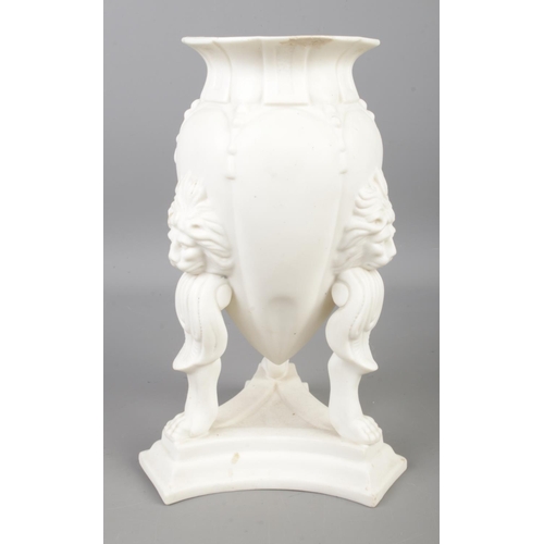 88 - A Parian ware urn featuring lion mask decoration and raised on lion paw feet. Approx. height 23cm.